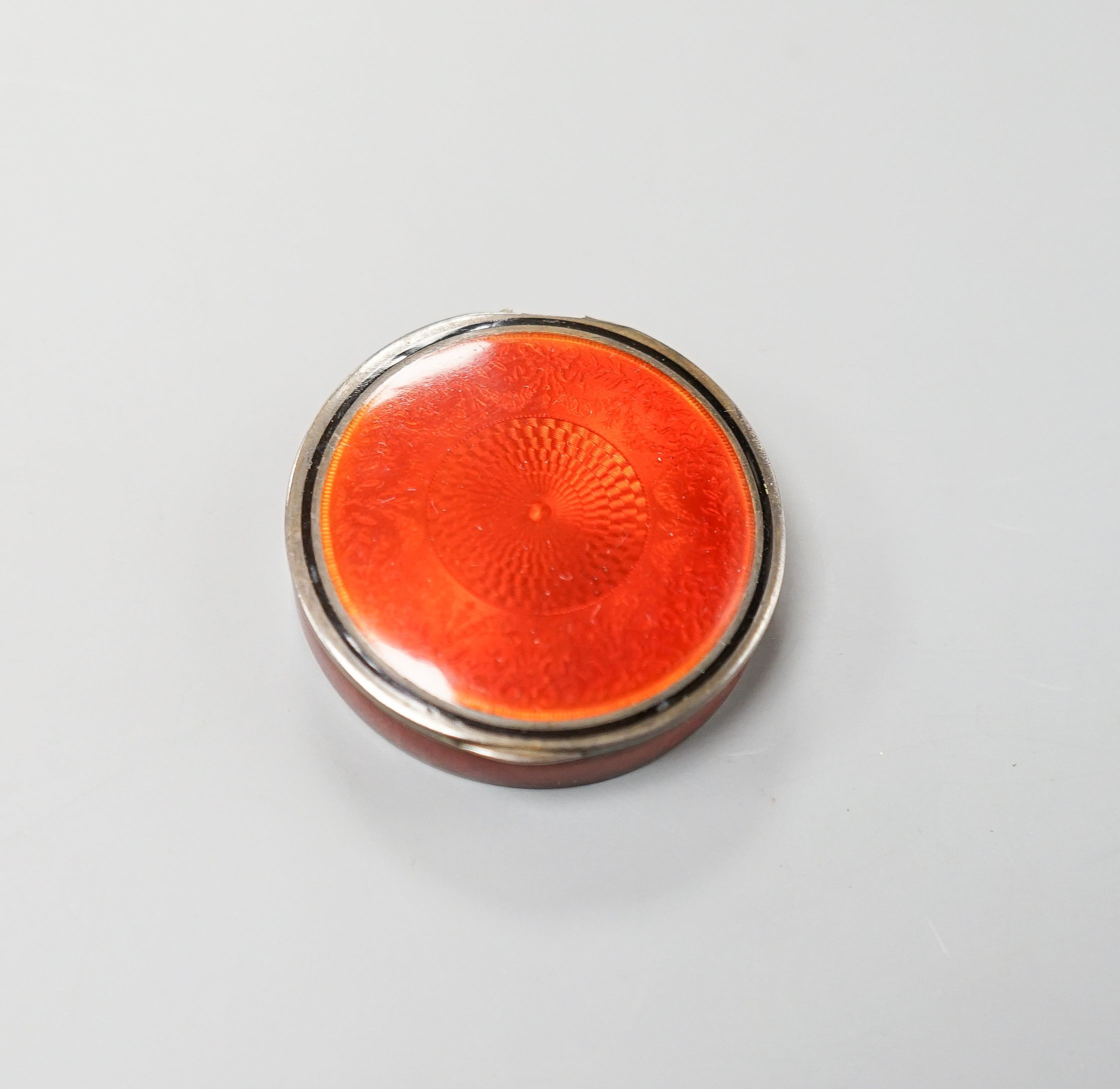 An early 20th century French engine turned white metal and red enamel circular pill box, 40mm.
